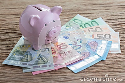 Pink piggy bank on pile of Euro banknotes on wooden table, financial savings money account or Europe economics concept, future gr Stock Photo