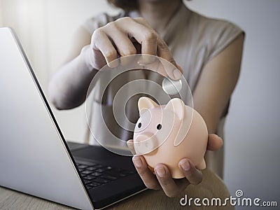 Pink piggy bank in woman`s hand and she put a blank silver money coin into it. Stock Photo