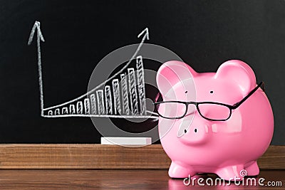 Pink piggybank with glasses on desk Stock Photo