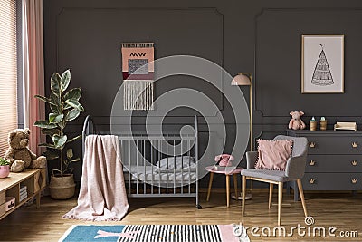 Pink pillow on grey armchair next to kid`s bed with blanket in b Stock Photo