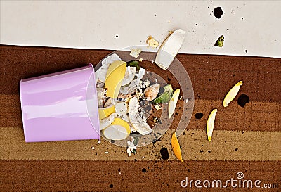 Pink plastic trashcan on floor with scattered organic waste Stock Photo