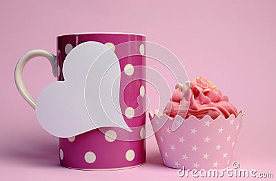 Pink polka dot coffee mug with pink cupcake and blank white heart shape gift tag Stock Photo