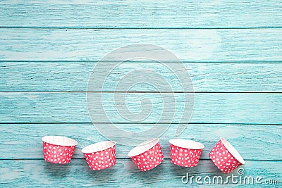 Pink polka dot cupcake cases on blue wooden floor. Stock Photo