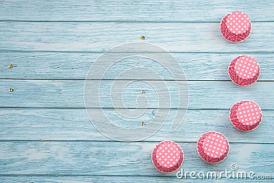 Pink polka dot cupcake cases on blue wooden floor. Kitchen equipment for bakery. Stock Photo