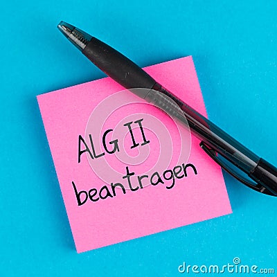Pink post with pen on blue background and german text ALG 2 beantragen, in english apply for unemployment benefits Stock Photo