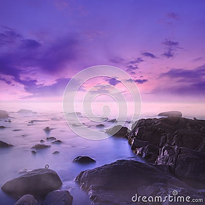 Pink and Purple Sunset Over Misty Rocks in the Sea Stock Photo