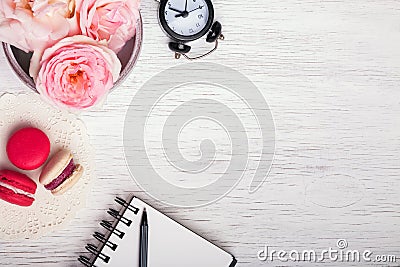 Pink roses, notepad, clock and macarons Stock Photo