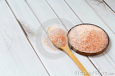 Fine pink Himalayan salt in wooden spoon on a white wooden background Stock Photo