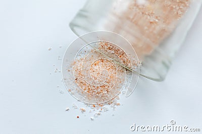 pink salt spill from small glass container on white background Stock Photo