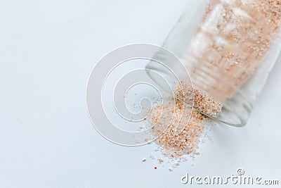 pink salt spill from small glass container on white background Stock Photo