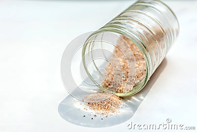 pink salt spill from small glass container on white background Stock Photo