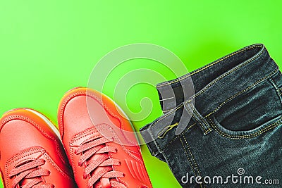 Pink sneakers and jeans on green background. Concept of sport and healthy lifestyle. Stock Photo