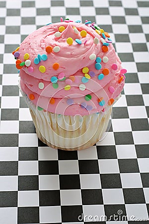 Pink sprinkle cupcake on checkered background Stock Photo