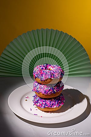 Pink sprinkle donuts in a spotlight from above Stock Photo
