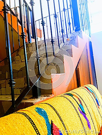 Pink stairway over colorful couch with Mexican turtle blanket iron wrought stairway Stock Photo