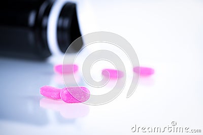Pink tablet pills on blurred background of opened cap amber bottle on white background. Expired medicine. Drug degradation Stock Photo