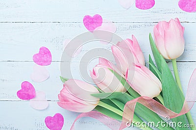 Pink tulip flowers decorated hearts and ribbon on blue table for Womans or Mothers day. Beautiful spring card. Top view. Stock Photo