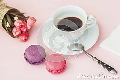 Pink and vioet macarons, macaroons, bouquet of spring flowers and cup of coffee, spoon, top view. Romantic morning, gift Stock Photo