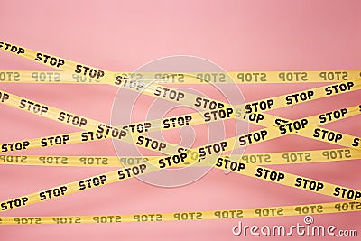 Pink wall with the yellow scotch tapes with inscriptions of word `stop` on it Stock Photo