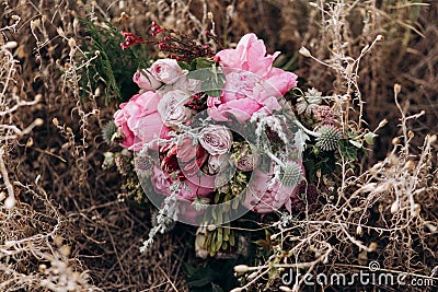 Pink wedding bouquet with a stone rose and peonies on the background of grass. Stock Photo