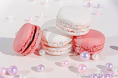Pink and white macarons on light wooden background with beautiful pearls decoration. French Pastel Macaroons. Blurred focus Stock Photo