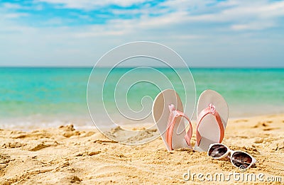 Pink and white sandals, sunglasses on sand beach at seaside. Casual fashion style flipflop and glasses. Summer vacation Stock Photo