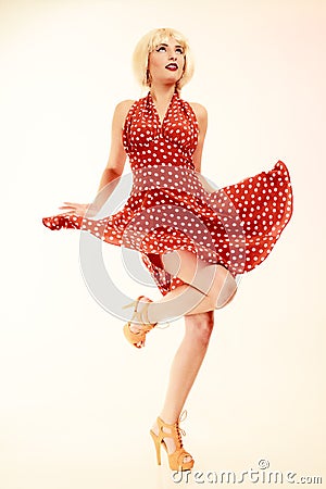 Pinup girl in blond wig retro dress dancing Stock Photo