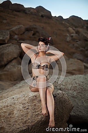 Pinup look dressed girl sitting in the rocks. Stock Photo
