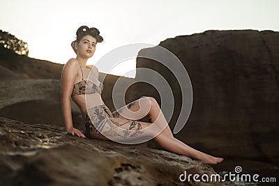 Pinup look dressed girl sitting in the rocks. Stock Photo