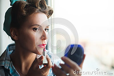 Pinup look dressed woman paints her lips with red lipstick Stock Photo