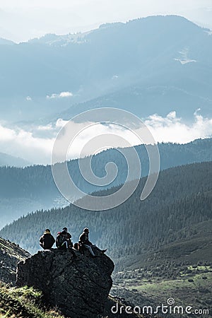 Pip Ivan, Ukraine - August 2, 2020: friends of three sitting on the rock at the top of the mountain enjoying the view Editorial Stock Photo