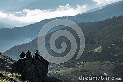 Pip Ivan, Ukraine - August 2, 2020: friends of three sitting on the rock at the top of the mountain enjoying the view Editorial Stock Photo