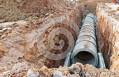 Digging and row of Concrete Drainage Pipe on a Construction Site .Concrete pipe stacked sewage water system aligned on site. Stock Photo