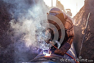 Pipe welding, Worker welding large water pipes in the road construction site Stock Photo