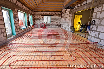 Pipefitter installing system of heating or underfloor heating installation. Water floor heating system interior. Stock Photo