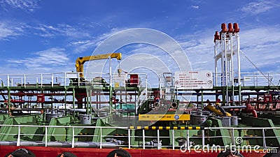 Pipelines system with crane on crude oil tanker at shipyard against white clouds and blue sky Editorial Stock Photo