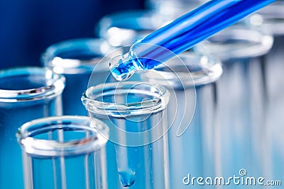 Pipette with blue liquid water drop fall in test tube in laboratory. Stock Photo