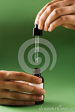 Pipette with Cannabidiol CBD oil in hand. CBD oil from the Cannabis plant to help reduce pain, anxiety, and sleep Stock Photo