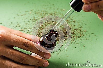 Pipette with THC oil in hand. THC oil from the Cannabis plant to help reduce pain, anxiety, and sleep disorders. Stock Photo