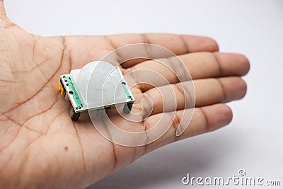 PIR sensor module for motion detection in robotics projects held in the hand. Useful electronic components to make electronic Stock Photo