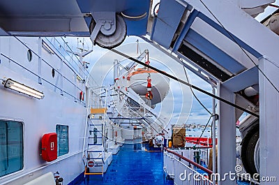 Piraeus Greece- Open deck corridor of a ferry boat with rescue boats and the port of Piraeus in background. Editorial Stock Photo