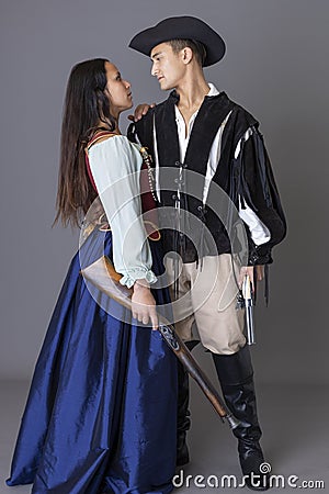 A pirate couple holding guns against a grey backdrop Stock Photo