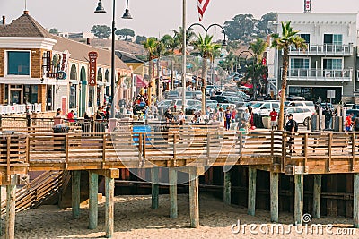 Pismo Beach boardwalk plaza. Beautiful sunny Sunday, restaurants, walking people, wooden boardwalk, street view Editorial Stock Photo