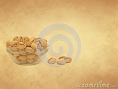 Pistachios in a glass bowl on old paper background Stock Photo