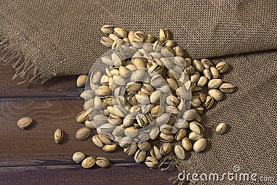 Pistachios nuts in burlap sack on wooden table Stock Photo