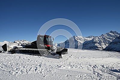 Pistenbully grooming slopes on a sunny day in Switzerland, Bernese Oberland Editorial Stock Photo