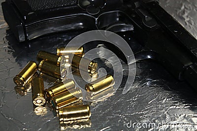 Pistol gun detail with brass golden munition on shiny silver desk Stock Photo