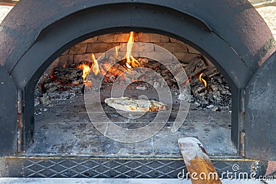 Pita, pizza is cooking in a wood fire in a stone oven Stock Photo