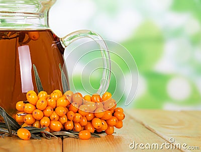 Pitcher drink and bunch sea buckthorn on abstract green background. Stock Photo