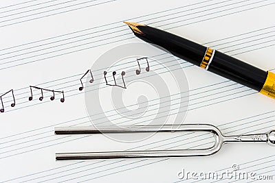 Pitchfork and pen on music sheet Stock Photo